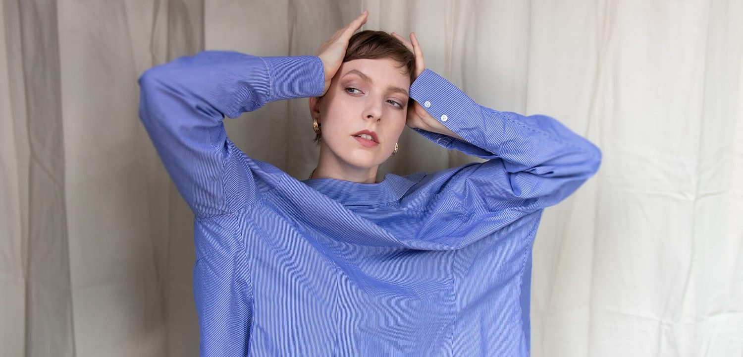 Junge Frau trägt hellblaues Hemd falsch herum - Sustylery