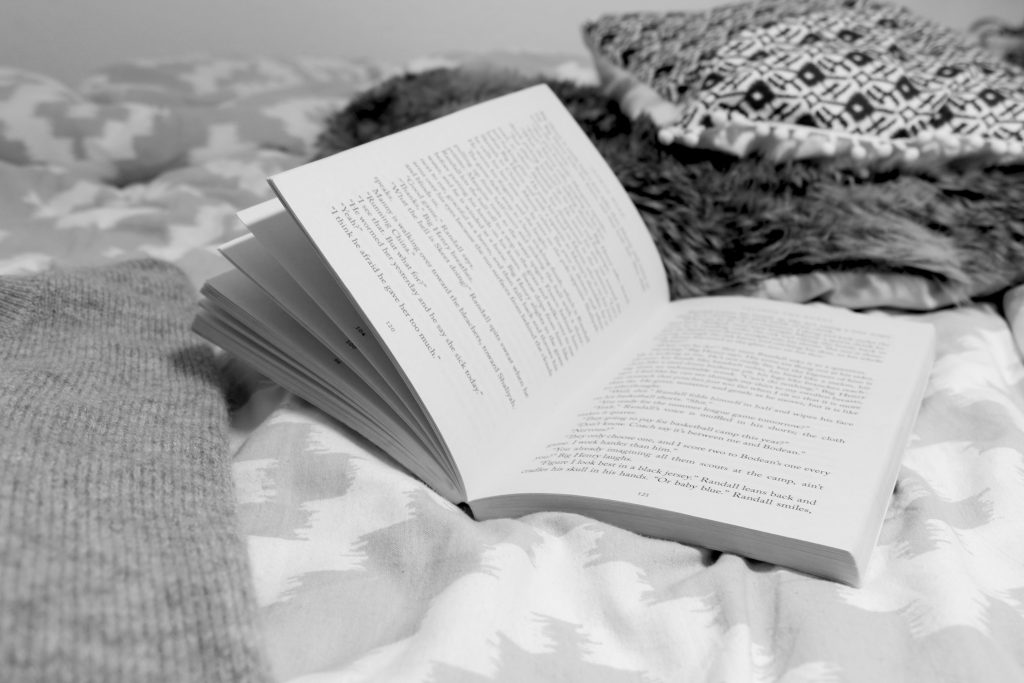 Ein Schwarz-Weiß Bild von einem aufgeschlagenen Buch im Bett