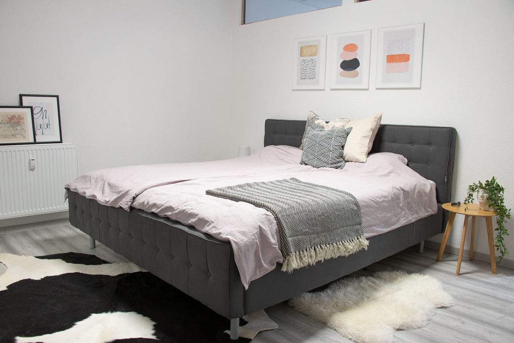 ein ordentlich gemachtes Bett in einem aufgeräumten Schlafzimmer